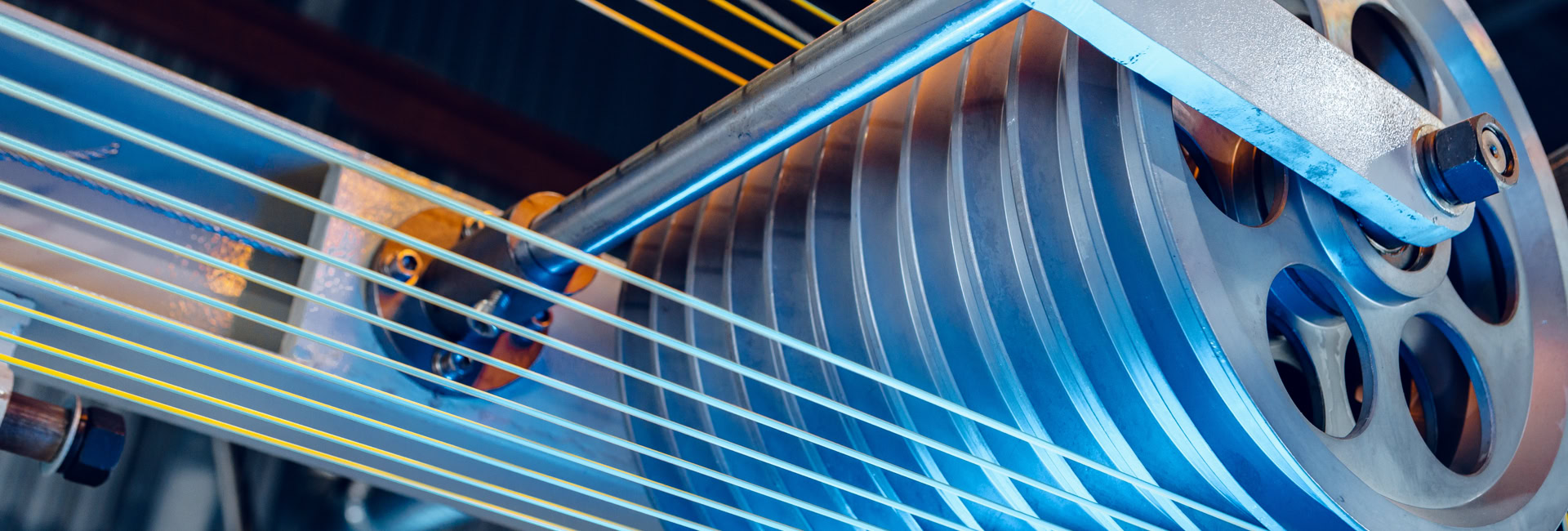 Close-up of an industrial machine with a series of pulleys or rollers and cables threaded through them, used in manufacturing or mechanical processes.